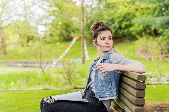 Photo of a female Chatham University student sitting on a bench outside on Shadyside Campus